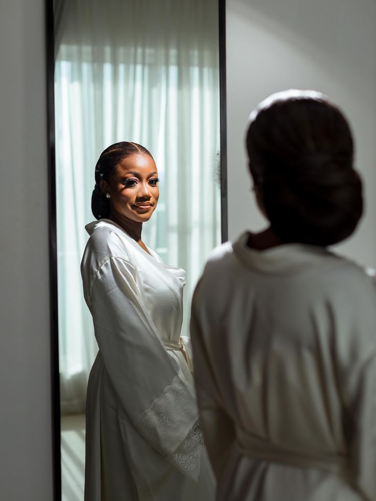 A bride in a white robe looking in the mirror